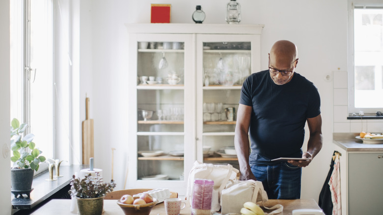 Man takes stock of recently purchased grocery items on kitchen table