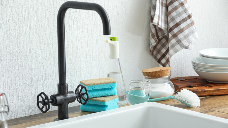 Baking soda, vinegar, and a cleaning brush next to a sink