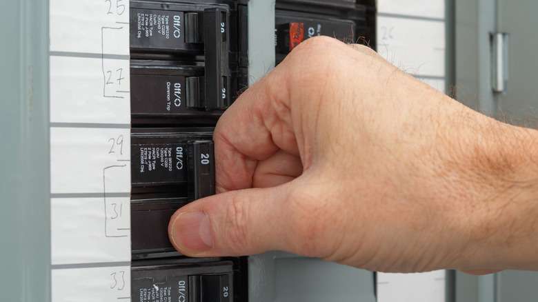 A person flipping a switch on the circuit breaker