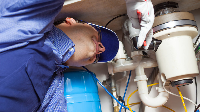 A man installing a garbage disposal