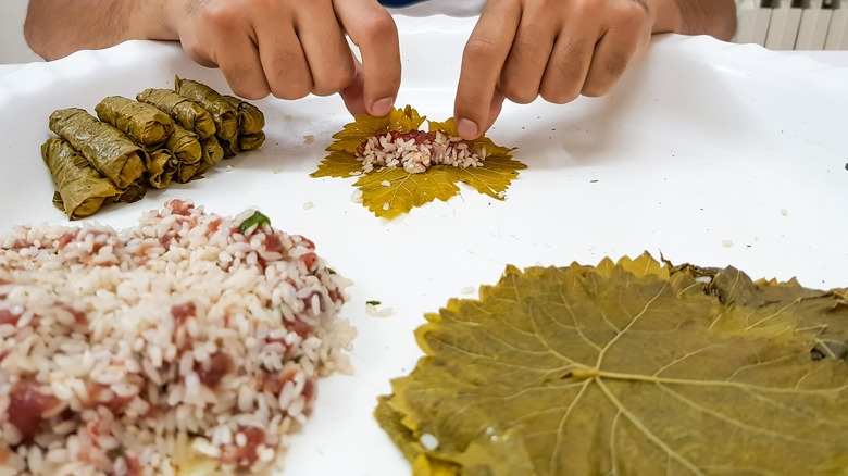 hands rolling grape leaves rice 