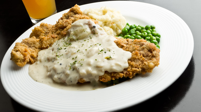 White plate of chicken fried steaks drenched in gravy