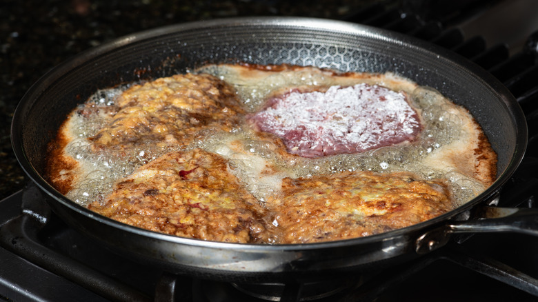 Chicken fried steaks frying in a frying pan