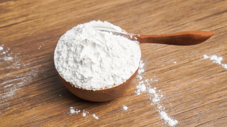 A wooden bowl of flour with a spoon in it