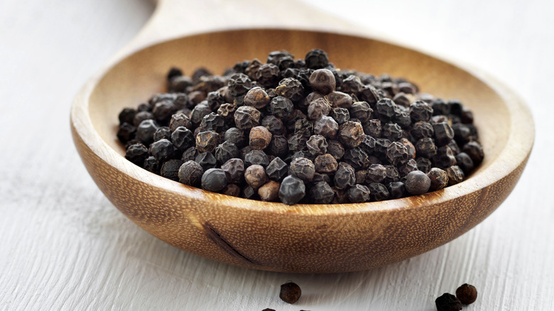 whole black peppercorns wooden bowl