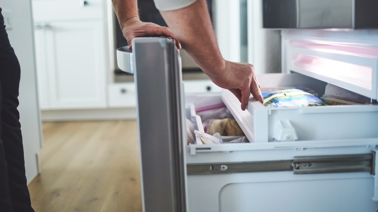 Hands opening freezer door 