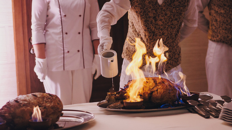 waiter flambéing a roast