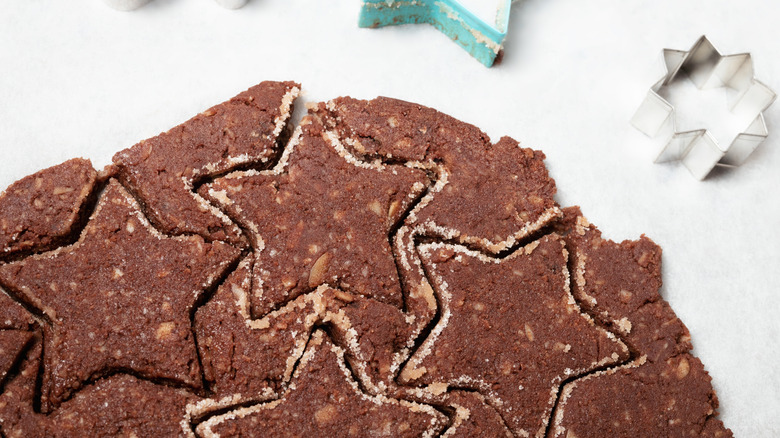 Brunsli cookie dough rolled on a white counter and cut into star shapes