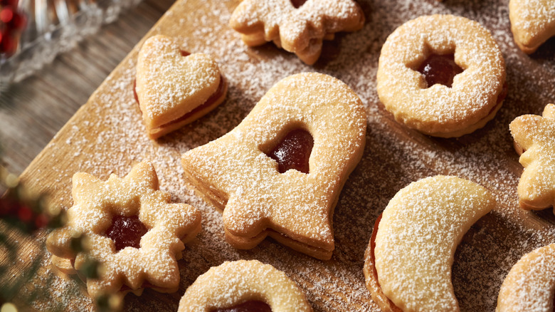 Linzer cookies layered on a cutting board, dusted with powdered sugar