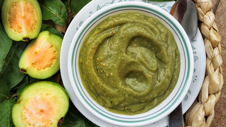 Guava chutney in bowl with guavas and spoon