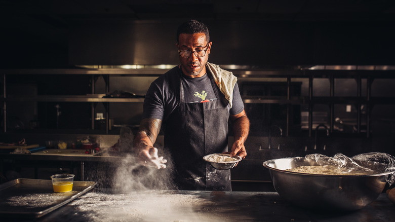 Male chef tossing flour on table