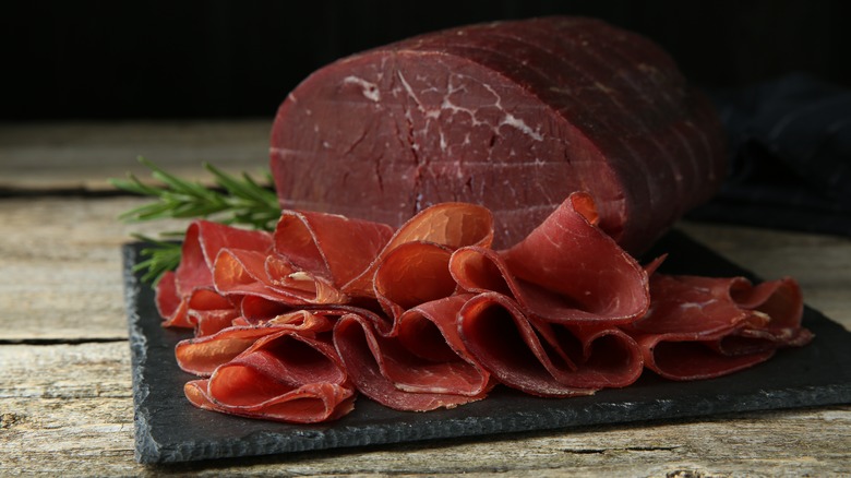 Sliced bresaola on black slate