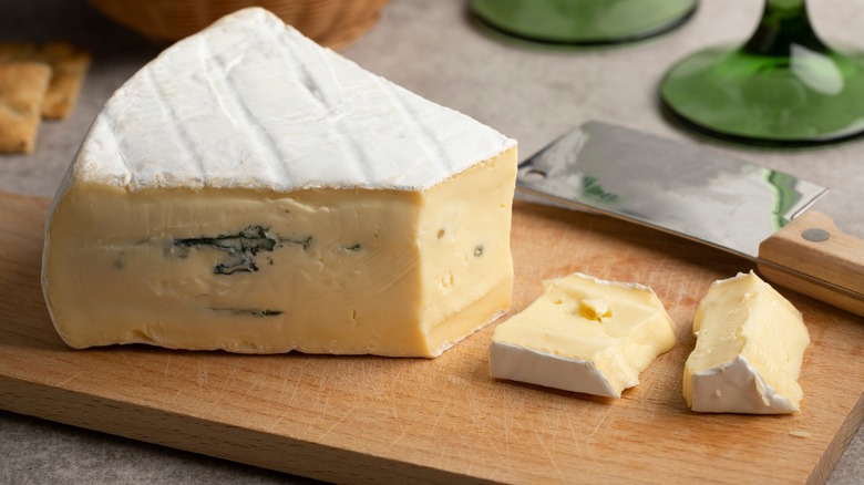 Wedge of cambozola on a wooden cutting board