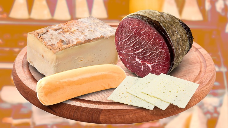 Deli meats and cheeses on a wooden platter against an orange-filtered deli background
