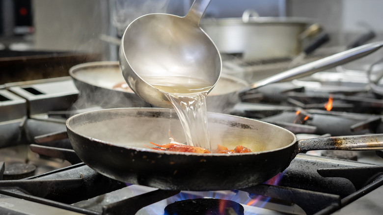 Ladle pouring water into pan