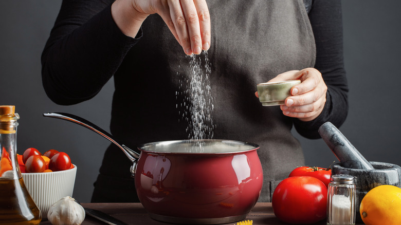 Chef sprinkling salt into pot