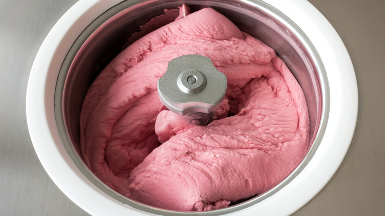 Homemade raspberry ice cream churning in a small professional ice cream machine