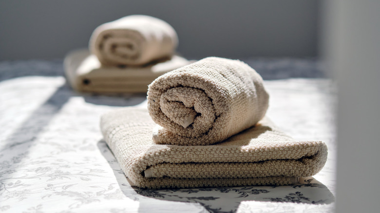 Close-up of two fresh clean folded rolled towels beige brown color on the bed in bedroom prepare for comfort accommodation in the hotel room or home, no people