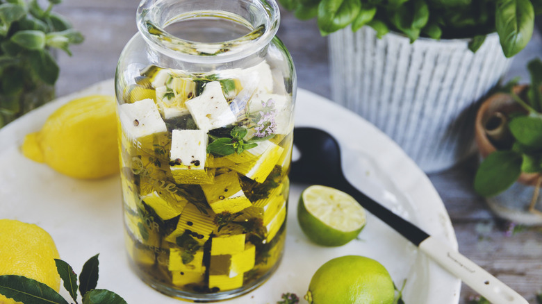 Feta cheese marinating with olive oil and herbs in a jar