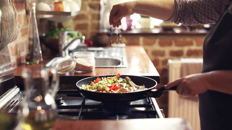 A cook salting veggies