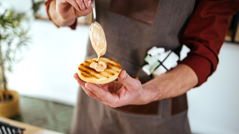 Sauce being spread on bun