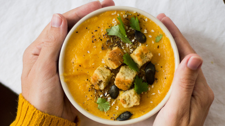 Person holding bowl of soup