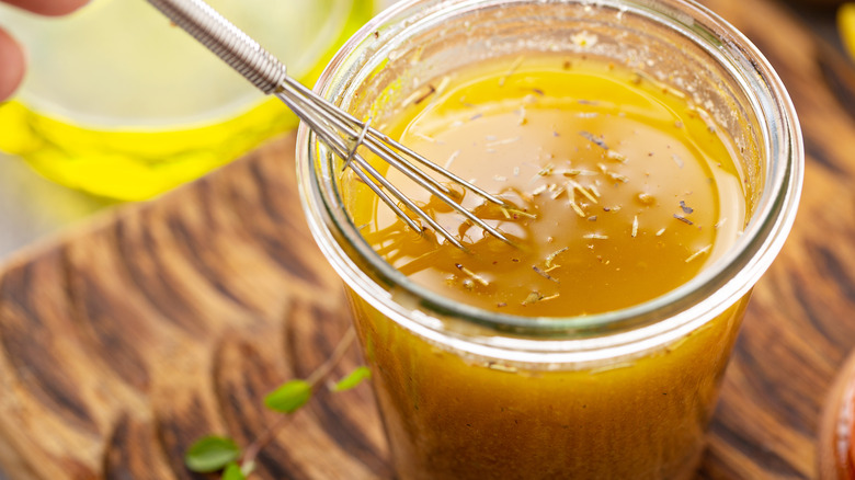 Homemade vinaigrette with whisk and jar