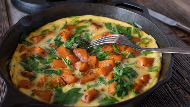 frittata in skillet with sweet potatoes and spinach