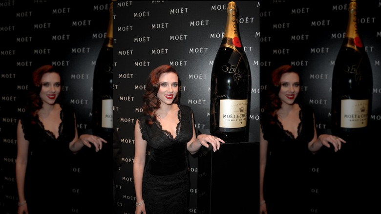 Scarlett Johansson smiling next to a Nebuchadnezzar Moët bottle