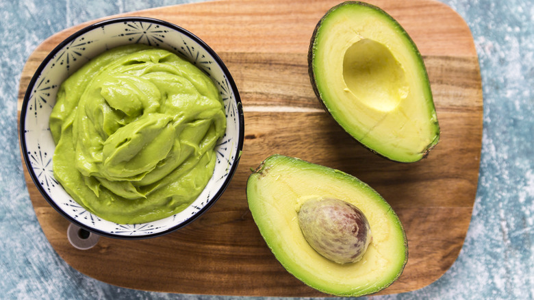 Ripe avocados on a brown chopping board