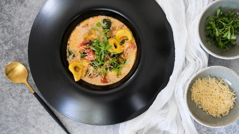 Black bowl of tortellini soup