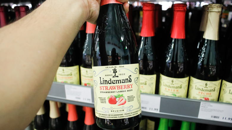 Person holding Lindeman's strawberry lambic bottle