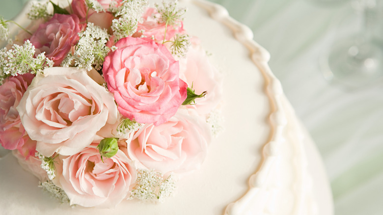 white cake decorated with fresh roses