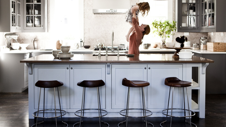 Parent lifting child into the air in a modern kitchen