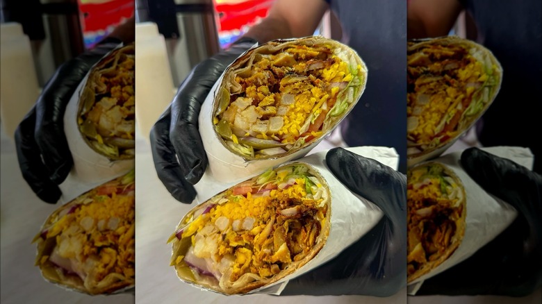 Hands holding shawarma wraps