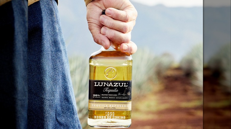 Hand holding a bottle of Lunazul Reposado outside