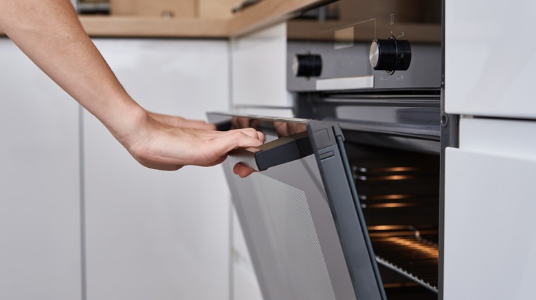 A hand opening an oven door