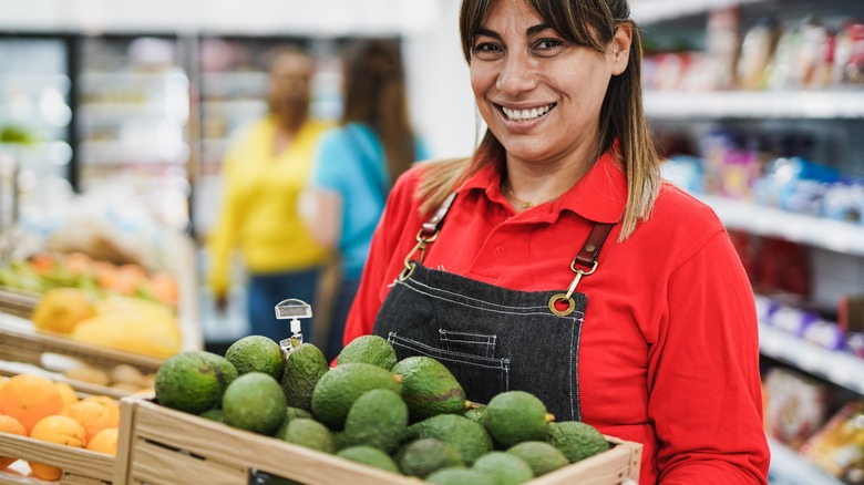 Woman holding crate of avocados