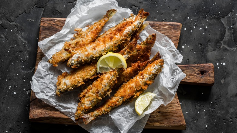 Whole fried sardines on wooden board