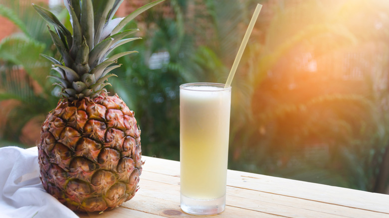 Pineapple juice next to a pineapple outside