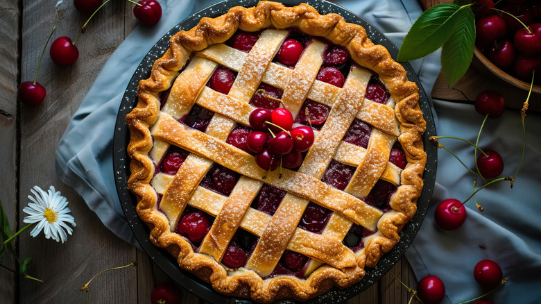 Cherry pie with latticework crust and fresh cherries on wooden table