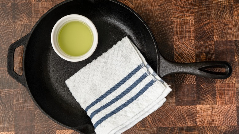 Ramekin of oil and towel in cast iron skillet