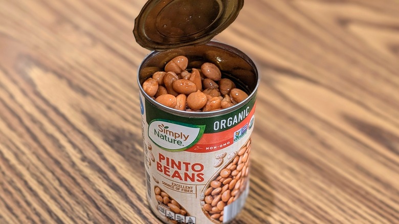 Open can of Simply Nature pinto beans on wood table