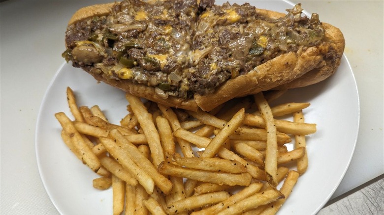 Philly cheesesteak and fries white plate