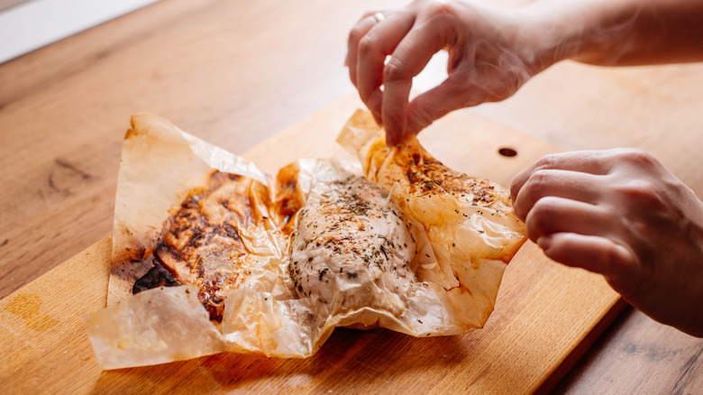 Person unwrapping chicken from parchment paper