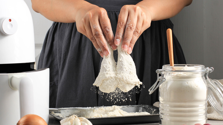 Person dredging chicken in flour