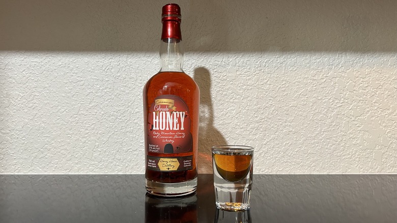 A bottle and shot of Honey House Distillery Cinnamon Honey Whiskey