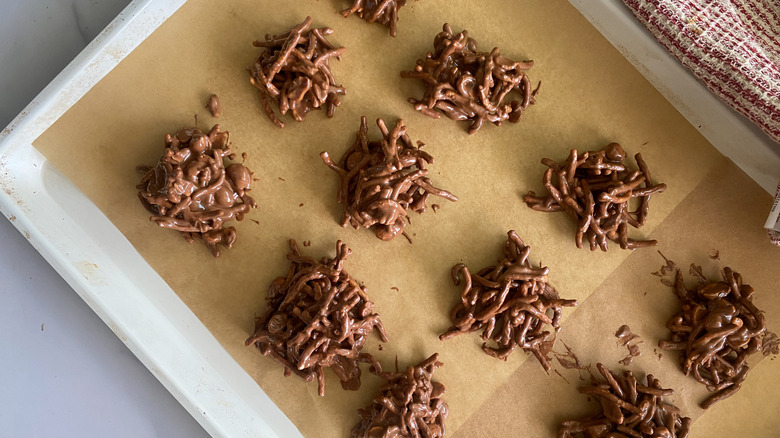 Chocolate-covered peanut butter haystacks on baking sheet