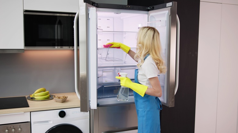 Woman cleaning fridge shelves