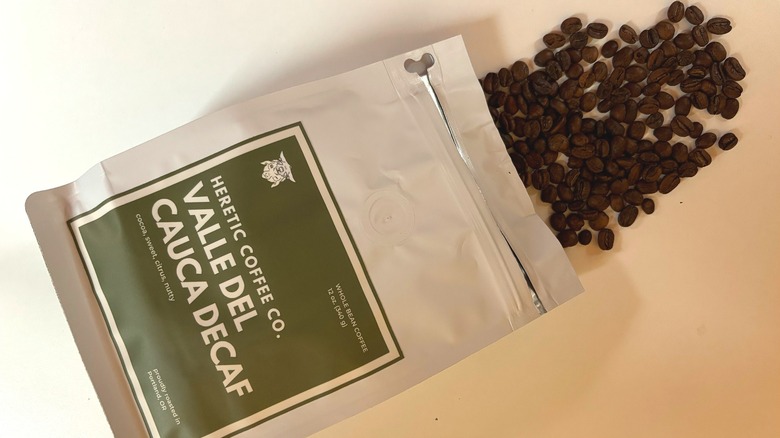 Coffee beans spilling out of a bag of Heretic Coffee onto a white table